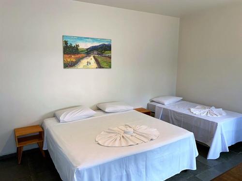 two beds in a room with a painting on the wall at Pousada Barra Bonita in Bonito