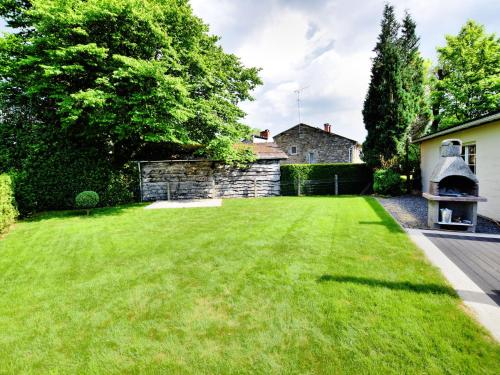 een grote tuin met een stenen muur en groen gras bij Modern holiday home in La Roche en Ardenne in Samrée