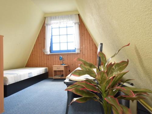 ein Zimmer mit einem Bett und einer Topfpflanze darin in der Unterkunft Peaceful Bungalow in Borgerende Germany with Large Terrace in Börgerende-Rethwisch