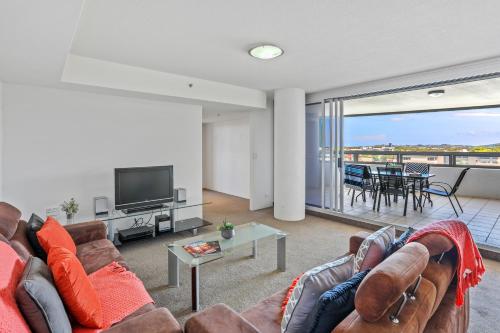 a living room with a couch and a television at Tweed Ultima Apartments in Tweed Heads