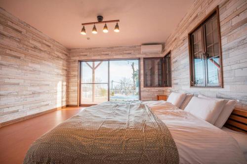 ein großes Bett in einem Zimmer mit einem großen Fenster in der Unterkunft むっくのおうち in Ito