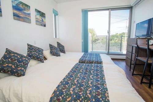 a large white bed in a room with a large window at HALE恩納村 Ys Casa in Onna