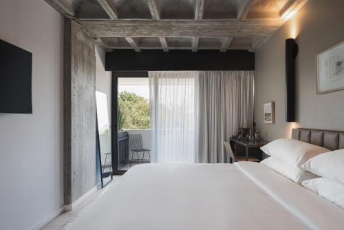 a bedroom with a large white bed and a window at Bellwort Hotel in Guadalajara