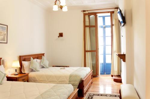 a hotel room with two beds and a television at Casa Hotel Las Plazas in Quito