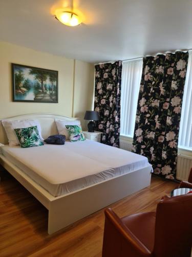 a bedroom with a large white bed with two windows at Tamar 2 in Katwijk aan Zee