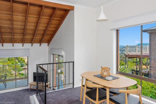 a dining room with a table and chairs and large windows at The Lookout in Hobart