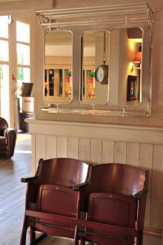a chair sitting in front of a mirror at Brit Hotel Essentiel Cholet in Cholet