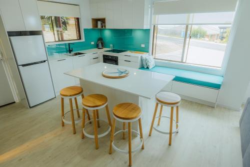 a kitchen with a white counter and stools in it at Blue Seas Holiday Villas in Scamander