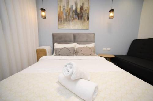 1 dormitorio con 2 camas con sábanas blancas y sofá en Geffen by the sea, en Eilat