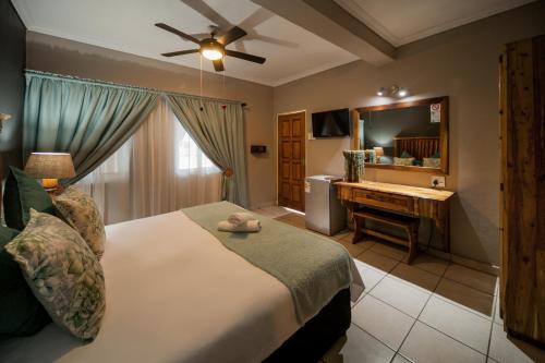 a bedroom with a bed and a desk with a mirror at Ivory Tusk Lodge in Tzaneen