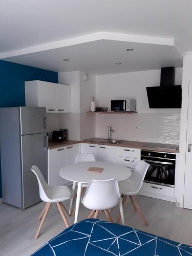 - une cuisine avec une table blanche et des chaises blanches dans l'établissement Studio Centre - Tout Confort - Tout à pied, à La Baule
