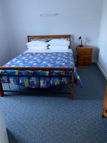 
a bedroom with a bed and a dresser at Orford Prosser Holiday Units in Orford
