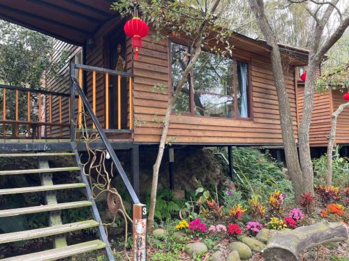 a tree house with a staircase and flowers at 山板樵愛面子民宿 in Sanyi