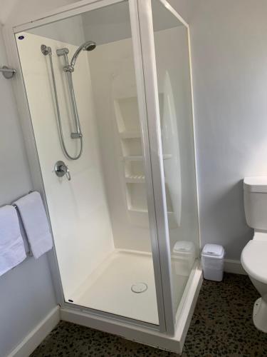 a white toilet sitting next to a shower in a bathroom at Orford Prosser Holiday Units in Orford
