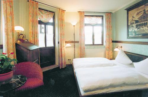 a hotel room with two beds and a chair at Hotel BB Bahnhof Bertsdorf in Olbersdorf