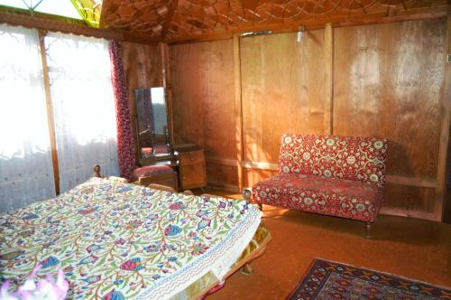 a bedroom with a bed and a chair at Houseboat Young Manhattan in Srinagar