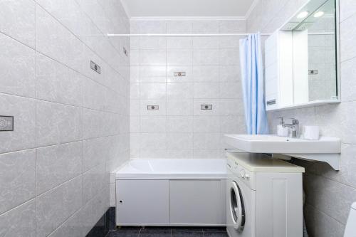 a white bathroom with a sink and a washing machine at New Avrora in Novosibirsk