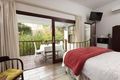 a bedroom with a bed and a balcony with a table at Royston Hall Historical Guesthouse in Umtentweni