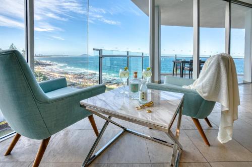 a living room with two chairs and a table and the ocean at Oceans Mooloolaba in Mooloolaba