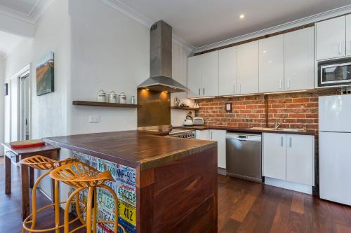 a kitchen with white cabinets and a brick wall at UrbanStyle Claremont Apartment in Perth