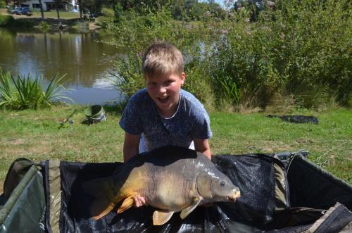 a young boy holding a large fish in a trap at L’Etang Carp fishing lake and Gite in Saint-Junien