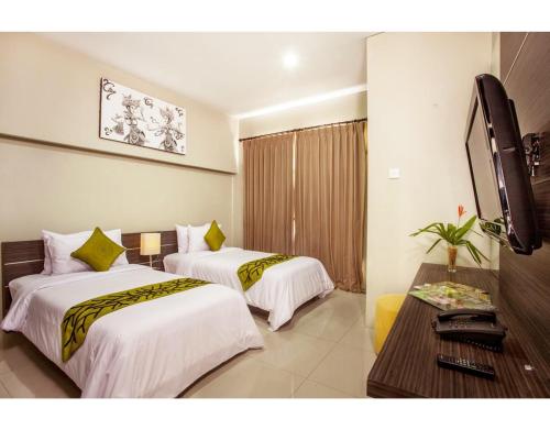 a hotel room with two beds and a television at ABISHA Resort Jimbaran in Jimbaran