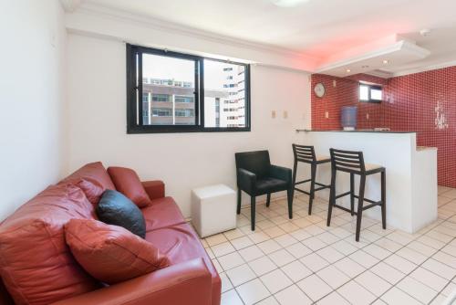 a living room with a couch and a kitchen at Boa Viagem Flat in Recife