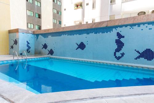 a swimming pool with blue tiles on the side of a building at Boa Viagem Flat in Recife