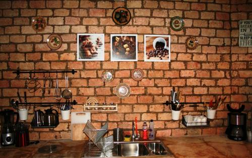 a kitchen with a sink and a brick wall with pictures at Casa Dos Patos in Flecheiras