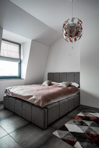 a bedroom with a bed and a chandelier at Apartamenty Ola in Lębork