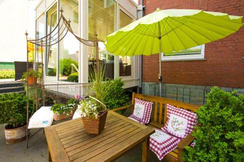 a wooden bench with a table and an umbrella at Hotel Wulff in Bad Sassendorf