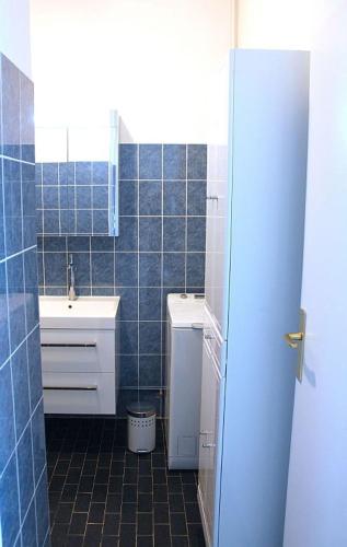 La salle de bains est pourvue de carrelage bleu, d'un lavabo et de toilettes. dans l'établissement Le Riviera Plage, à Nice