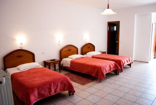 three beds in a room with red sheets on them at Hotel Gigilos Omalos in Omalós