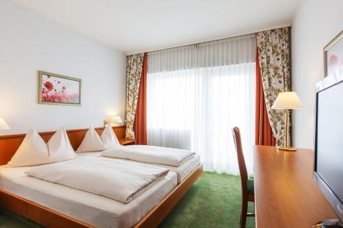 1 dormitorio con cama, escritorio y ventana en Landzeit Motor-Hotel St. Valentin, en Sankt Valentin