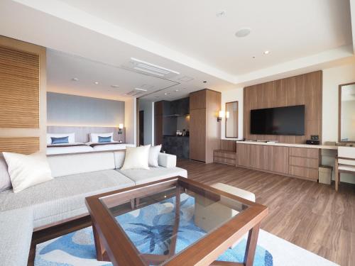 a living room with a couch and a tv at Hiyori Ocean Resort Okinawa in Onna