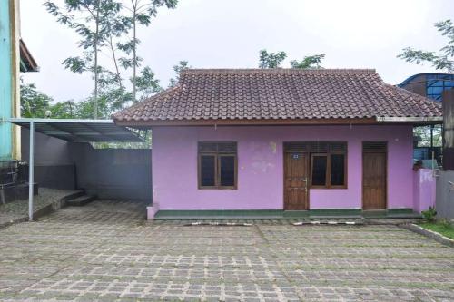 una pequeña casa morada con techo de baldosa en RedDoorz near Lokawisata Baturaden, en Purwokerto