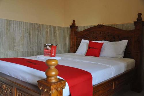 プルウォケルトにあるRedDoorz near Lokawisata Baturadenのベッドルーム1室(赤と白の枕が備わるベッド1台付)