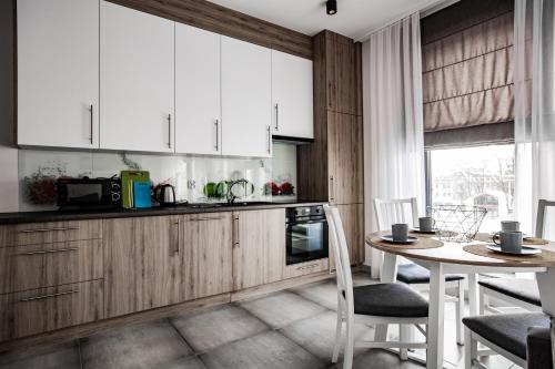 a kitchen with white cabinets and a table with chairs at Apartamenty Ola in Lębork