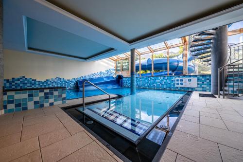 a large swimming pool with blue tiled walls and ceilings at Dolomiten Residenz - Sporthotel Sillian in Sillian