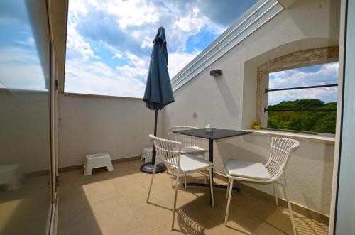 a balcony with a table and chairs and a window at App & Rooms Juraga in Bale