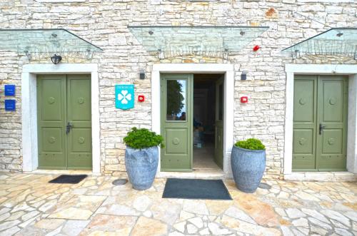 a stone building with two green doors and potted plants at App & Rooms Juraga in Bale