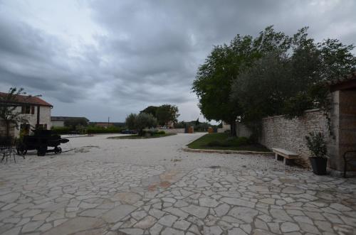 a stone walk way with a bench and a tree at App & Rooms Juraga in Bale