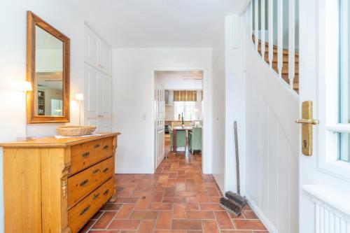 a hallway with a wooden dresser and a mirror at Landhaus Windspiel in Midlum
