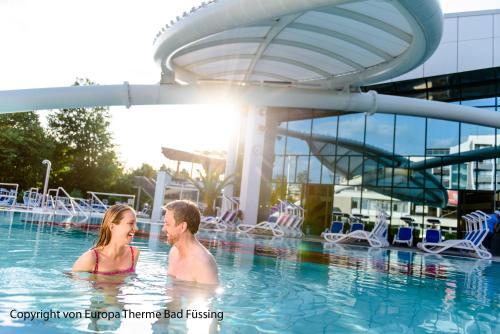 un hombre y una mujer en el agua en una piscina en Hotel FrechDachs en Bad Füssing