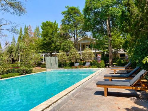 a swimming pool with lounge chairs next to a house at Diamond Hill Resort in Nong Nam Daeng