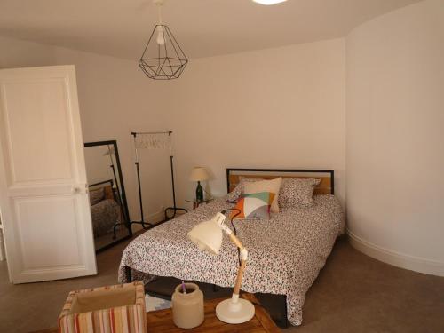 um quarto com uma cama com um candeeiro em La petite vadrouille - coeur urbain d'Epernay em Épernay