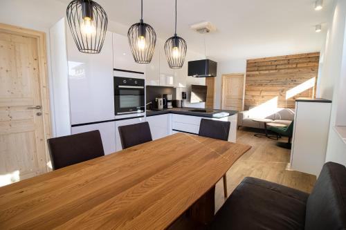 eine Küche und ein Esszimmer mit einem Holztisch und Stühlen in der Unterkunft Kreischberg Suites by ALPS RESORTS in Sankt Lorenzen ob Murau