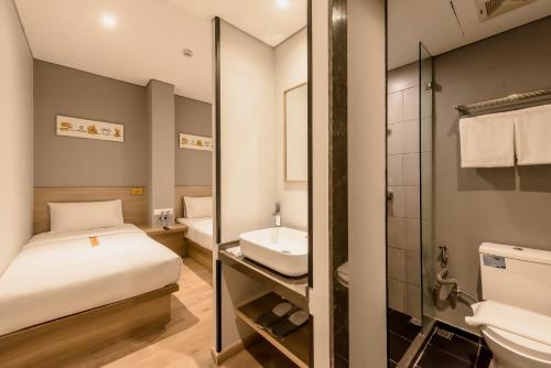 1 dormitorio con cama, lavabo y espejo en Yellow Bee Tanah Abang, en Yakarta