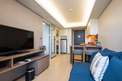 a living room with a blue couch and a flat screen tv at Maitria Hotel Rama 9 Bangkok - A Chatrium Collection in Bangkok