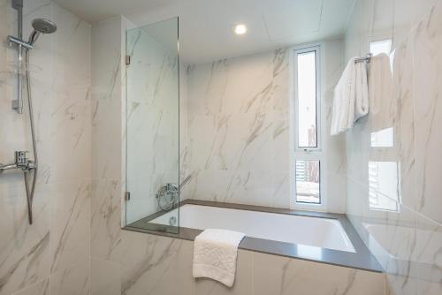 a bathroom with a tub and a glass shower at Maitria Hotel Rama 9 Bangkok - A Chatrium Collection in Bangkok